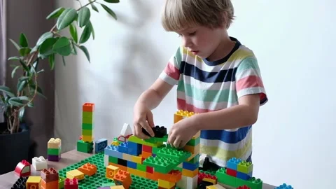 Cute boy 4 years old playing with colorful plastic toy bricks at the table at 動画素材 111367573