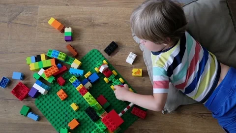Cute boy 4 years old playing with colorful plastic toy bricks on the floor at Stock Footage 111368361