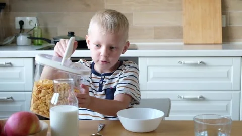 Cute boy 4 years old having breakfast cornflakes with milk at the table at home. Stockbeeldmateriaal 111369254