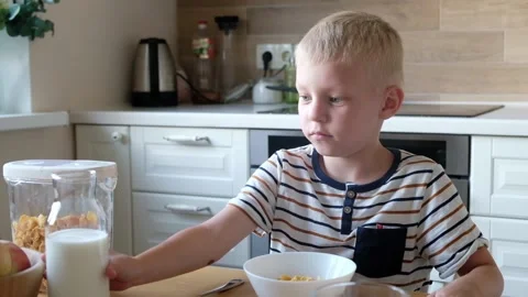 Cute boy 4 years old having breakfast cornflakes with milk at the table at home. Vídeos de archivo 111369353