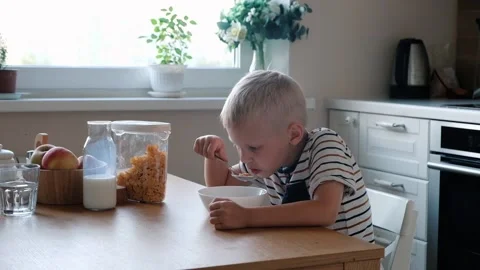 Cute boy 4 years old having breakfast cornflakes with milk at the table at home. Stockbeeldmateriaal 111405736