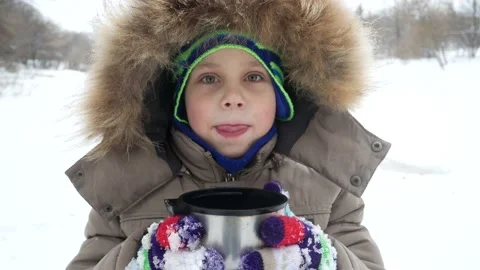 A cute boy 5-6 years old drinks tea from a thermos in a winter park on a walk Stock Footage 161320660