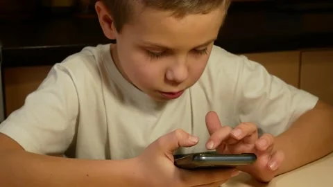 Cute boy 6-7 years old playing the application on the mobile phone Stock Footage 168147000