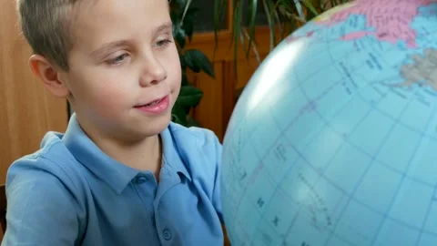 Cute boy 6-7 years old is looking at the globe Stock Footage 168407556