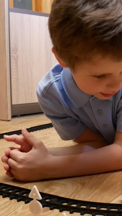 A cute boy of 6-7 years old plays with a childrens railway Stock Footage 317850039