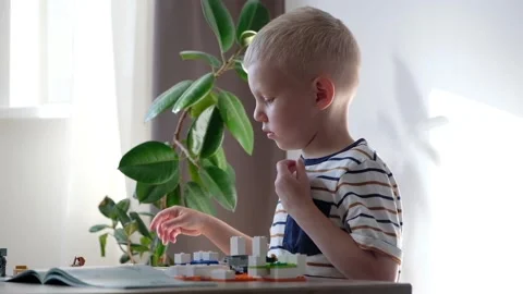 Cute boy 6 years old playing with colorful plastic toy bricks at the table at 스톡 동영상 108654257