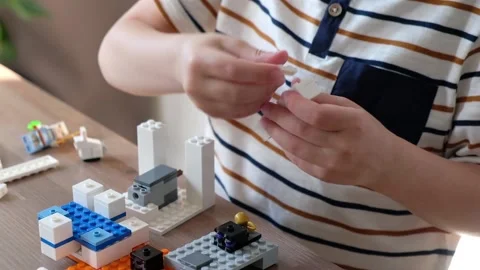Cute boy 6 years old playing with colorful plastic toy bricks at the table at Stockbeeldmateriaal 108654357