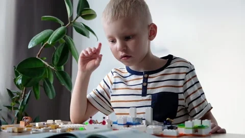 Cute boy 6 years old playing with colorful plastic toy bricks at the table at Video stock 108654430