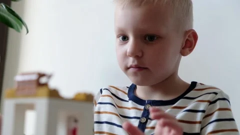 Cute boy 6 years old playing with colorful plastic toy bricks at the table at Stock-Footage 108654639