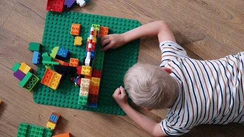 Cute boy 6 years old playing with colorful plastic toy bricks on the floor at Stock Footage 111368638