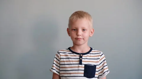 Cute boy 6 years old playing looking at camera and smiling. Grey background Stock Footage 111368947