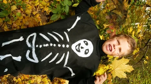 A cute boy of 7-8 years old in a costume with the image of a skeleton rejoices Stock Footage 205889181