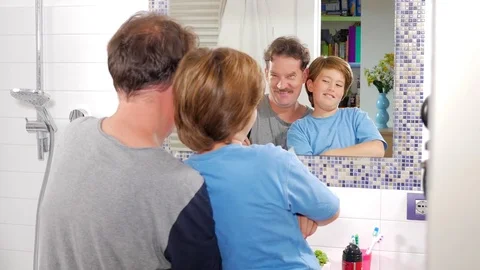 Cute boy and father in front of mirror playing showing muscles making funny e Stock Footage 82357652