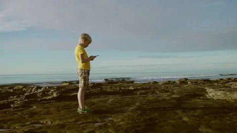Cute boy on a beach with a smartphone Stock Footage 75744722