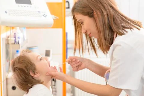 Cute boy being checked in throat in a clinic Stock Photos