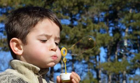 Cute boy blowing soap bubbles Stock Photos