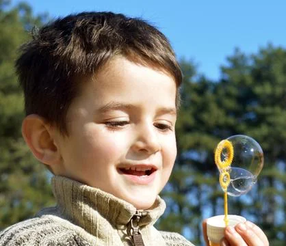 Cute boy blowing soap bubbles Stock Photos