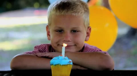 Cute Boy Blows out Candle on Blue Cupcake at Birthday Party Stock Footage 8986098
