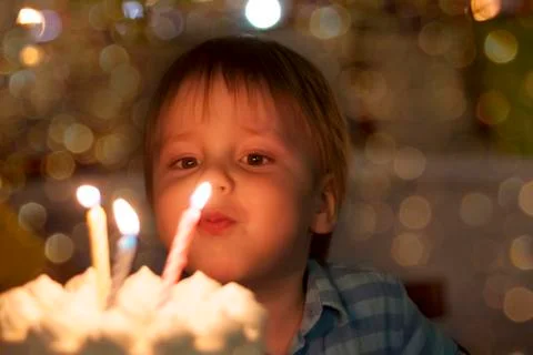 Cute boy blows out candles on his third birthday. The child's birthday. Stock Photos
