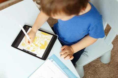 Cute boy in blue tshirt using digital tablet or computer for drawing his picture Stock Photos