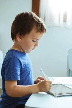 Cute boy in blue tshirt using digital tablet or computer for drawing his picture Stock Photos