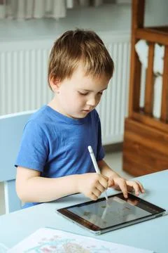 Cute boy in blue tshirt using digital tablet or computer for drawing his picture Stock Photos