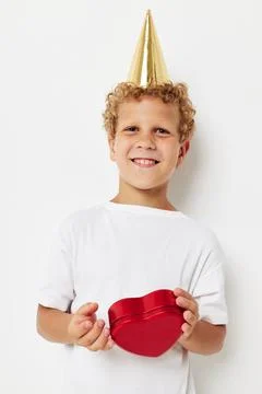 Cute boy with a cap on his head a gift box in the shape of a heart Stock Photos