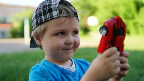 Cute boy in a checkered cap with a red toy car in his hands Foto stock
