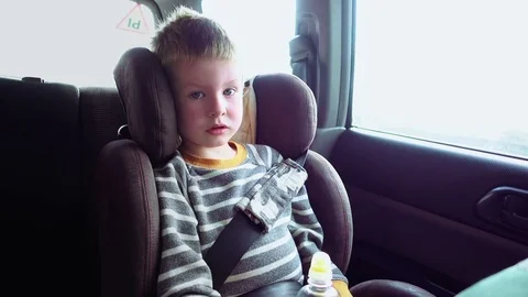 Cute boy in a child car seat plays with a toy Stock Footage