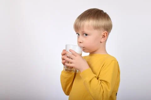 Cute boy child in yellow sweater drinks water Stock Photos