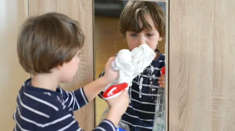 Cute boy cleaning the mirror using some spray Stock Footage 48951004