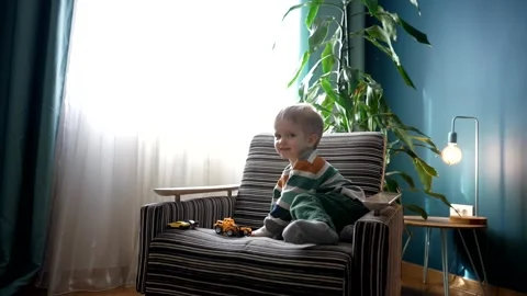 Cute boy climbs on sofa with car toys. Stock Footage 243275023