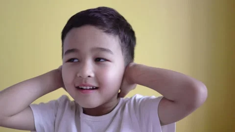 Cute boy covers ears with palms on colour background Stock Footage 195037794