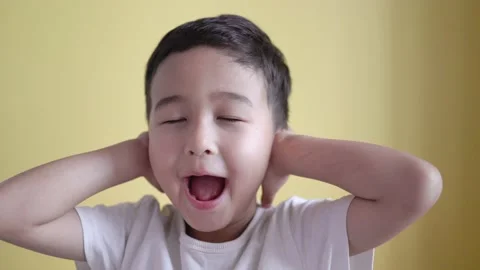 Cute boy covers ears with palms on colour background Stock Footage 195037846