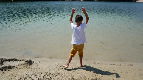 A cute boy is dancing on the sandy shore of the beach. Travel and Leisure Stock Footage 141181156