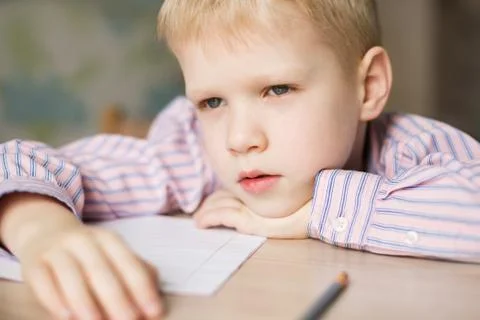 Cute  boy doing his homework and looking tired. Stock Photos