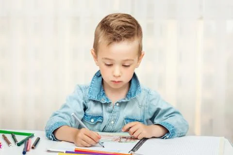 Cute boy doing homework writing and painting. Children paint Stock Photos