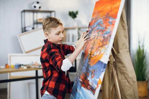 Cute boy drawing abstract pattern on canvas with hands Stock Photos