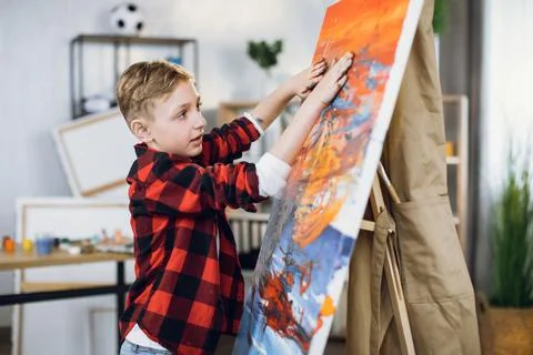 Cute boy drawing abstract pattern on canvas with hands Stock Photos