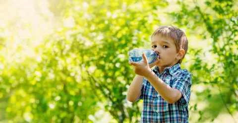 Cute boy drinking a bottle of pure water in nature. Stock Photos