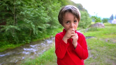 Cute boy eating bread in nature near river Stock Footage 54605471