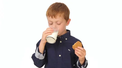 Cute boy eating a cookie and drinking milk, white background Video stock 65776120