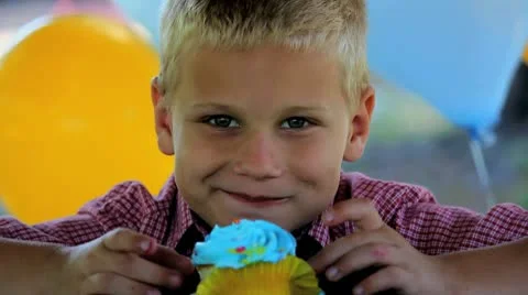 Cute Boy Eats Blue Cupcake at Birthday Party, Getting Icing on his Face Stock Footage 8986092