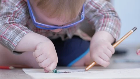 Cute boy in funny glasses draws with both hands on paper at home Stock Footage 88960010