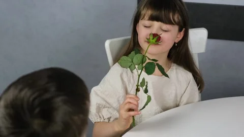 A cute boy gives a dark-haired pretty girl flowers, a red rose Stock Footage 146788816