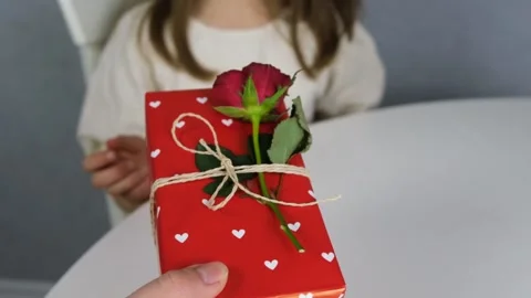 A cute boy gives a dark-haired cute girl a gift box. Stock Footage 146789892