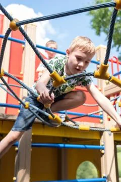 Cute boy having fun and climbing on the outdoor playground. Stock Photos