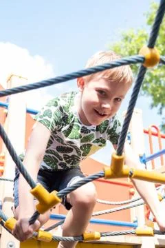 Cute boy having fun and climbing on the outdoor playground. Stock Photos