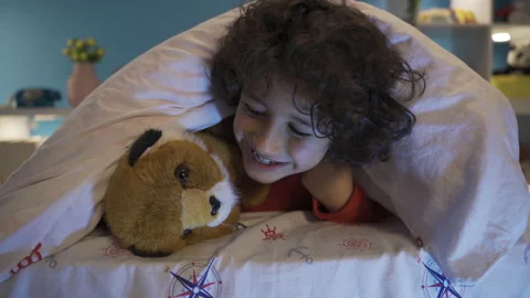 Cute boy hiding under the bed with his t... | Stock Video | Pond5