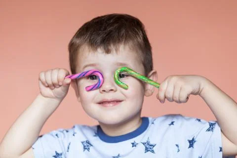 A cute boy holding two candy sticks. Stock Photos